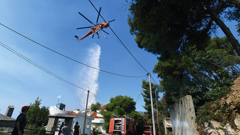 مروحية تحاول إطفاء النيران المشتعلة شمال العاصمة أثينا.   أ.ب