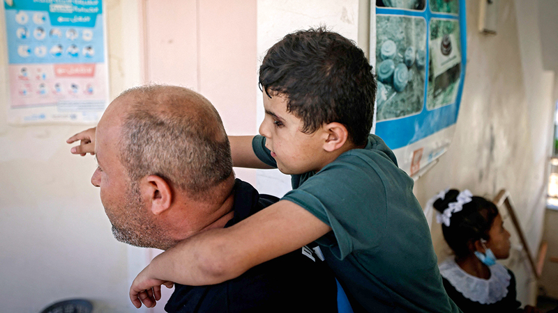 الأب يحمل ابنه ليُجلسه على مقعد الدراسة.  أ.ف.ب
