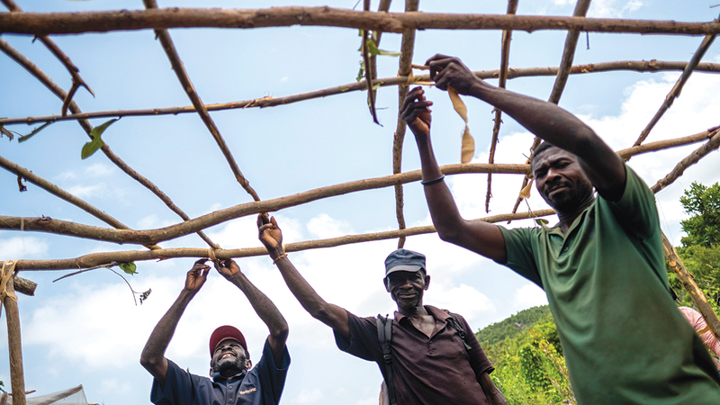 3 رجال يبنون كوخاً مؤقتاً لإيوائهم داخل المخيم.   رويترز