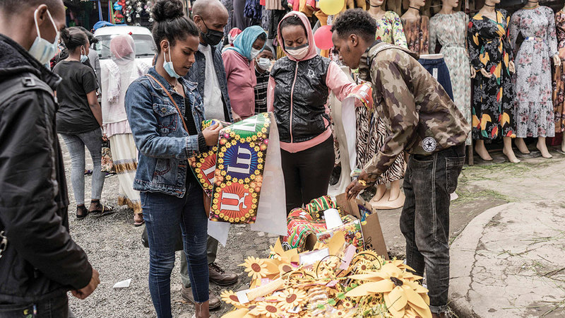 مشترون يلتفون حول بائع ديكور منزلي استعداداً للعام الإثيوبي الجديد.  أ.ف.ب