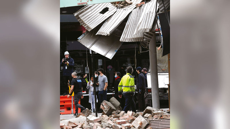 سكان المدينة يتجمعون أمام أحد المباني المتهدمة.  أ.ف.ب