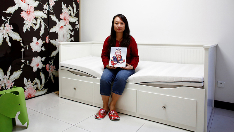 داي شياولي تحمل صورة ابنتها التي أُخذت منها.  أرشيفية