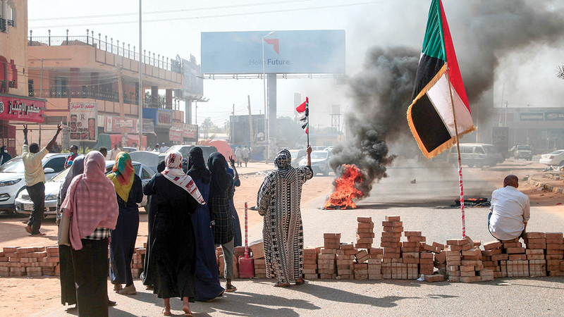 متظاهرون يرفعون علم السودان بجوار حاجز من الطوب في الخرطوم أمس.    أ.ف.ب