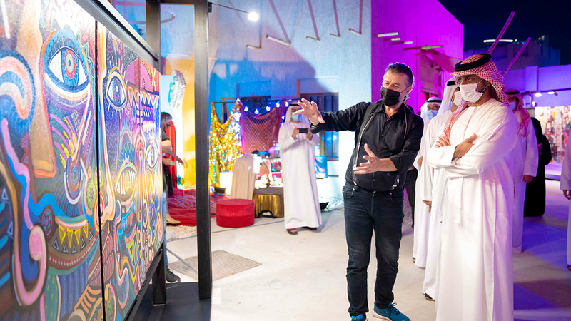 عمار بن حميد النعيمي خلال مشاهدته إحدى اللوحات المشاركة في المهرجان.  وام