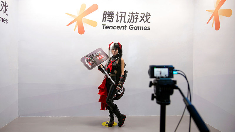 صينية تقف لالتقاط صورة أمام ملصق إعلاني لواحدة من ألعاب الفيديو التي لم تعد مجرد لعبة فيديو في ظل السباق المحموم بين شركات التكنولوجيا.   رويترز