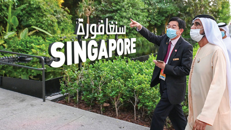 محمد بن راشد خلال زيارته جناح سنغافورة.   وام