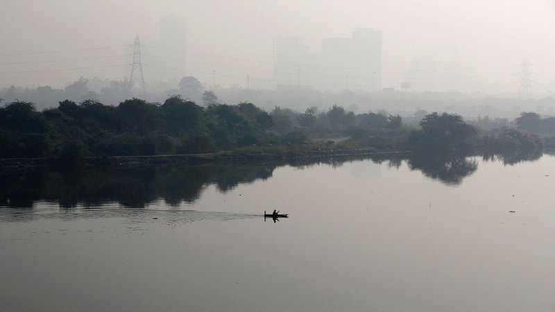 قارب يشق طريقه في النهر الذي أحاط به ضباب التلوث من كل جانب في نيودلهي.   رويترز