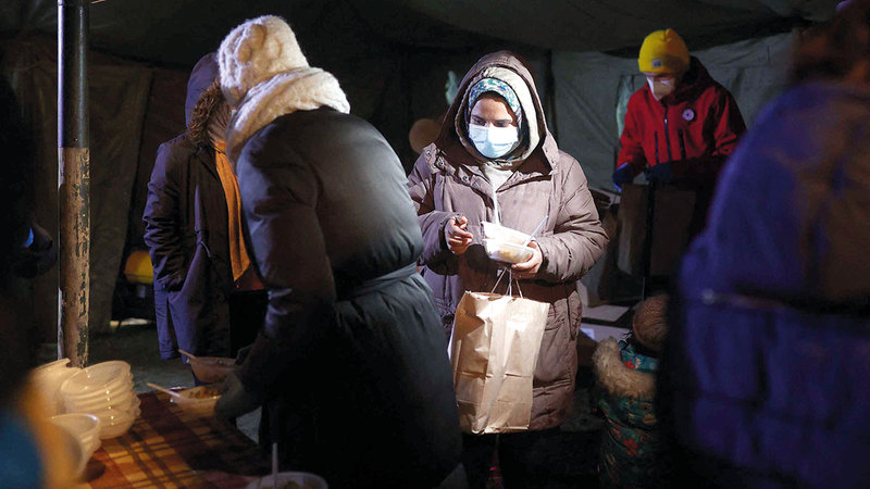 مهاجرون يحصلون على وجباتهم من خيمة خارج مخيّمهم.   أ.ف.ب