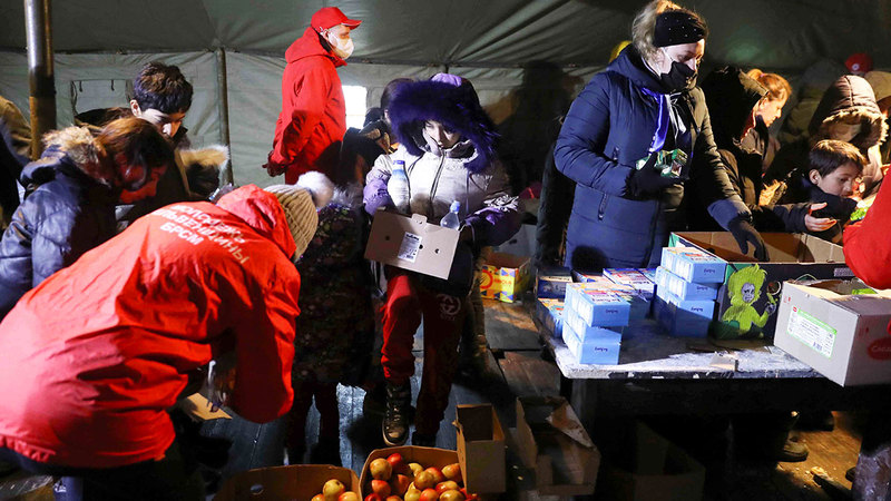 مهاجرون يحصلون على حصص غذائية في مخيّم ايواء أقيم على المنطقة الحدودية. أ.ب