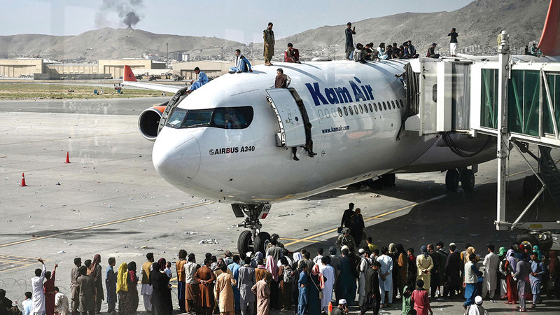 الأفغان يعتلون سطح إحدى الطائرات في مطار كابول رغبة في الهرب من بطش «طالبان».   أ.ف.ب