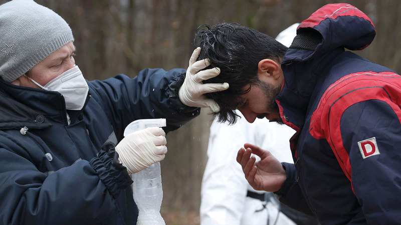 مهاجر يرش شعره ببخاخ ليحمي رأسه من الثلج المتساقط على المكان.   رويترز