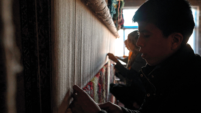 أفغان ينسجون سجادة من الحرير باهظة الثمن داخل البيوت.   أ.ف.ب