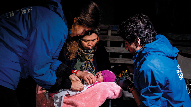 متطوعون يساعدون إحدى المهاجرات التي كانت ضمن مَن تم إنقاذهم.   أ.ف.ب