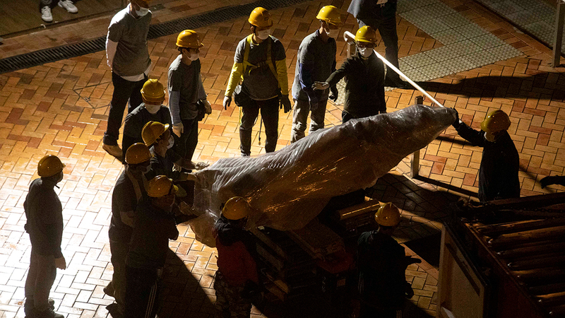 العمال يتابعون إنزال التمثال المثير للجدل.   أ.ب