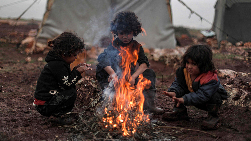 أطفال عائلة «أبوحسين» يستمتعون بالحصول على قسط من الدفء رغم المخاطر.    أ.ف.ب