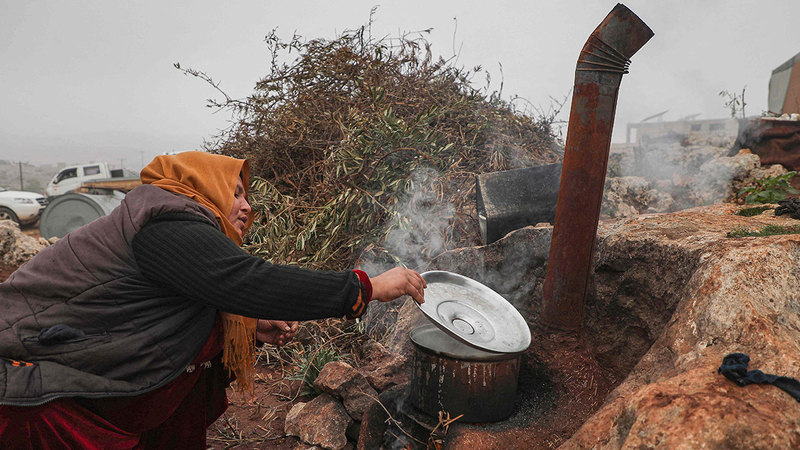 «أم محمد» تطبخ على الحطب في الهواء الطلق.   أ.ف.ب