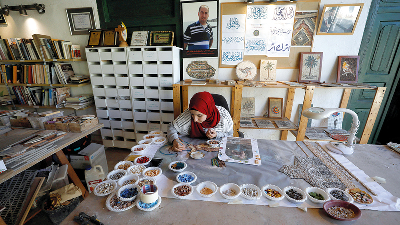 سيدة فلسطينية تجدد ألواحاً من الموزاييك وتبدع نسخاً من القطع التاريخية في مدينة أريحا.   رويترز
