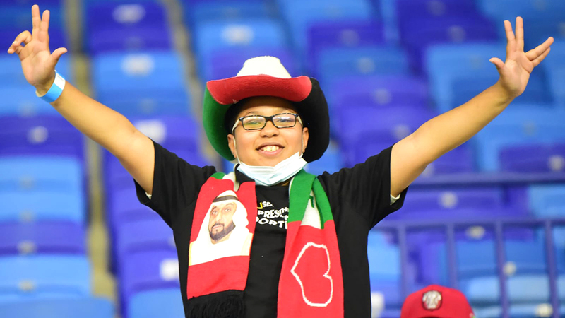 مشجع المنتخب الوطني يشهر علامة النصر على مدرجات استاد آل مكتوم.	  تصوير: أسامة أبوغانم