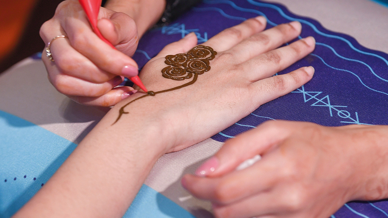 النساء في جناح صميم يوفرن للزائرات رسومات باستخدام الحناء.   تصوير: باتريك كاستيلو