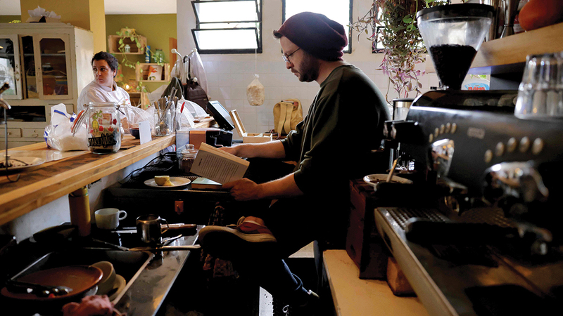 صانع القهوة يقرأ ويعمل في المقهى.   أ.ف.ب