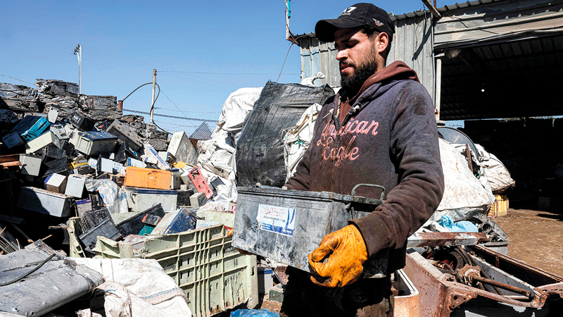 عامل فلسطيني يحمل إحدى البطاريات لإعادة بيعها من أجل إعادة التدوير. 	  أ.ف.ب