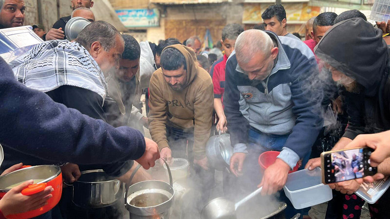 أبناء وليد الحطاب يتشاركون لطهو «الجريشة» للفقراء.   الإمارات اليوم