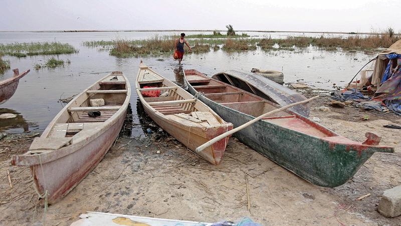 صياد سمك يحمل شبكته وسط مياه بحيرة الرزازة التي تواجه نضوباً في الأسماك بسبب الجفاف وشح المياه.	   أ.ف.ب