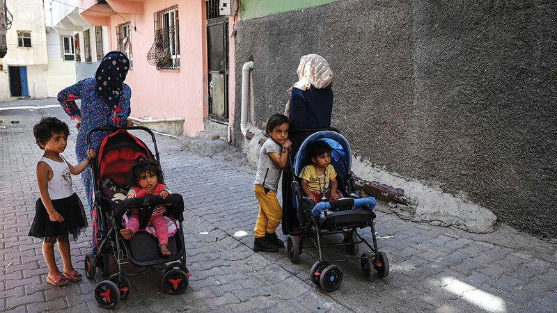 سيدتان سوريتان تسيران مع أطفالهما في أحد الشوارع وسط جو من التوتر مع الأتراك في شانلي أورفا. أ.ف.ب