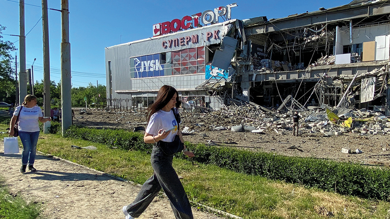 امرأتان أوكرانيتان تمران قبالة مركز تسوّق دمره القصف الروسي لمدينة خاركيف الأوكرانية. رويترز