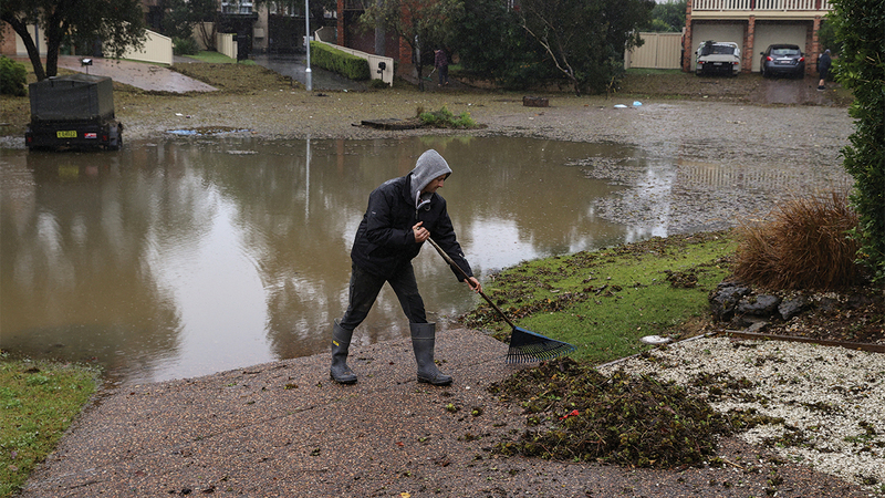 يزيل الحطام الذي تسببت فيه مياه الفيضان من أمام منزله. رويترز