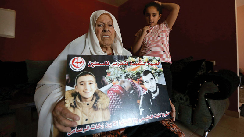 «أم خالد» تحتضن صورة لحفيديها اللذين قتلتهما القوات الإسرائيلية.   الإمارات اليوم