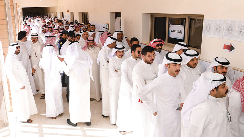 كويتيون ينتظرون خارج مركز اقتراع للإدلاء بأصواتهم خلال الانتخابات البرلمانية بمدينة الكويت. إي.بي.إيه
