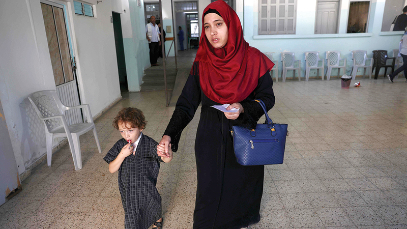 ياسر خيلة برفقة والدته لدى عودته إلى البيت بعد تلقّي العلاج.   أ.ف.ب