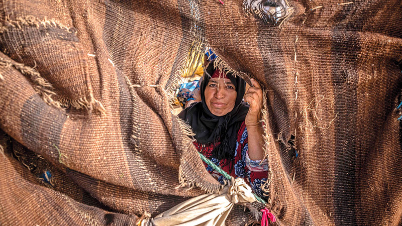 سيدة تطل برأسها من داخل إحدى الخيام وسط الصحراء. أ.ف.ب