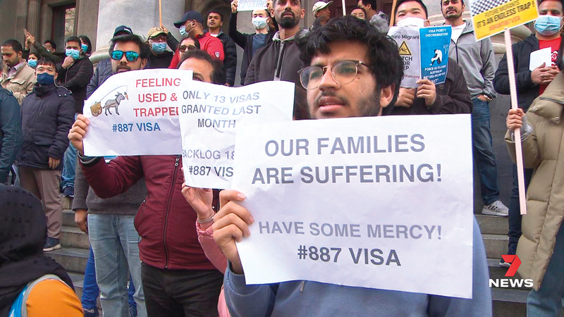أحد العمال المهاجرين يرفع لافتة كُتب عليها «عوائلنا تعاني». أرشيفية