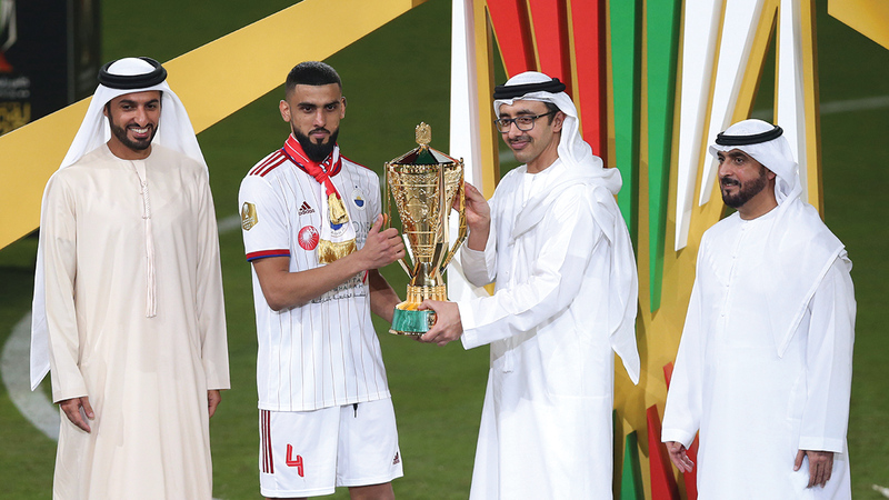 عبدالله بن زايد خلال تقديم الكأس إلى قائد فريق الشارقة شاهين عبدالرحمن  بحضور راشد بن حميد. من المصدر