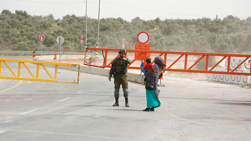 جندي إسرائيلي يمنع سيدة فلسطينية من الخروج من «عزون».   الإمارات اليوم