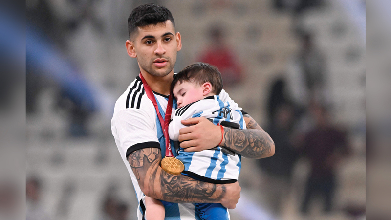 المدافع الأرجنتيني كريستيان روميرو يحمل ابنه فالنتينو خلال احتفاله بالفوز في المباراة النهائية. أ.ف.ب