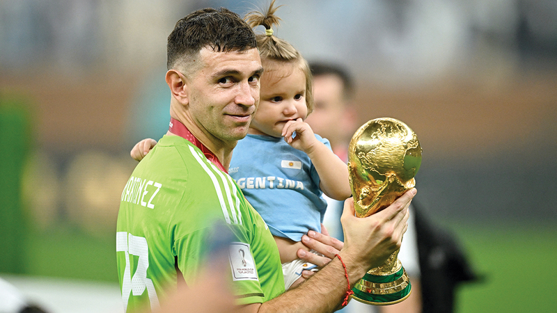 حارس الأرجنتين إيميليانو مارتينيز يحتفل بالكأس مع طفله عقب مراسم التتويج. رويترز