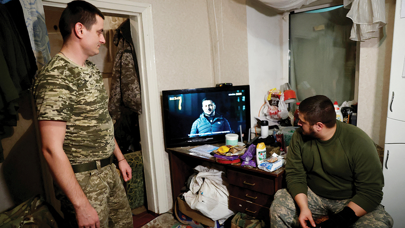 جنديان أوكرانيان يشاهدان خطاب زيلينسكي في استراحة عسكرية.   رويترز