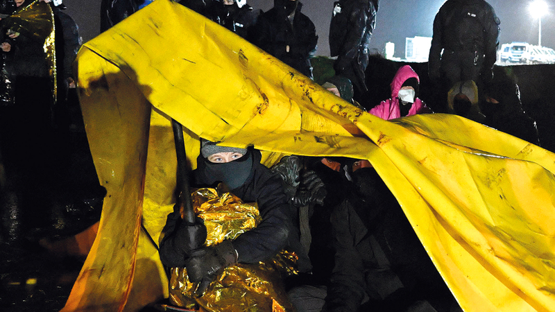 النشطاء يحتمون من المطر بالجلوس تحت شادر سميك.  أ.ف.ب