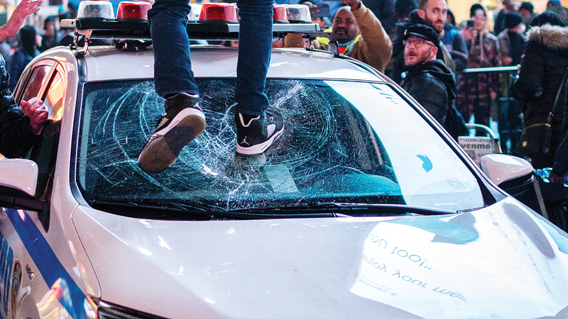 متظاهر يحطم الزجاج الأمامي لسيارة شرطة خلال الاحتجاجات على وفاة نيكولز.   رويترز