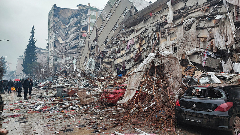 أشخاص يقفون أمام المباني المنهارة في أعقاب الزلزال الذي وقع في منطقة كهرمان ماراس في تركيا. رويترز