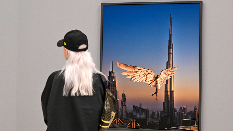إحدى الزائرات تتأمل عملاً سيريالياً للفوتوغرافي الإيطالي أنطونيو سابا يصور فتاة تطير بالقرب من «برج خليفة».   تصوير: باتريك كاستيلو