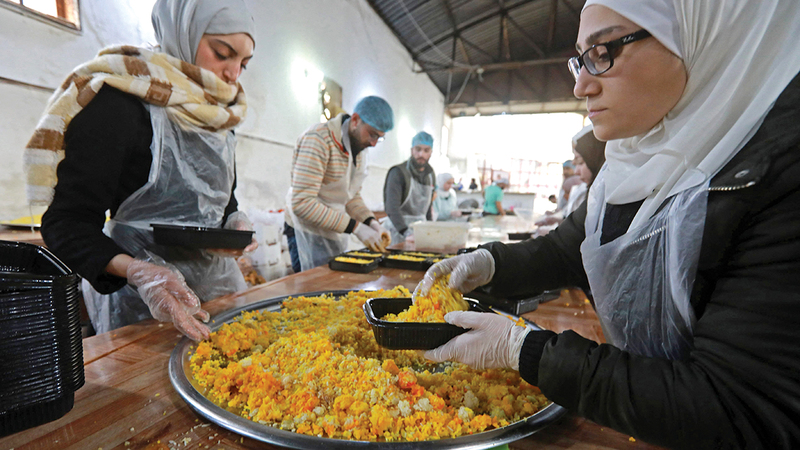 يحضرون الوجبات للمحتاجين في مخيمات الإيواء.  أ.ف.ب