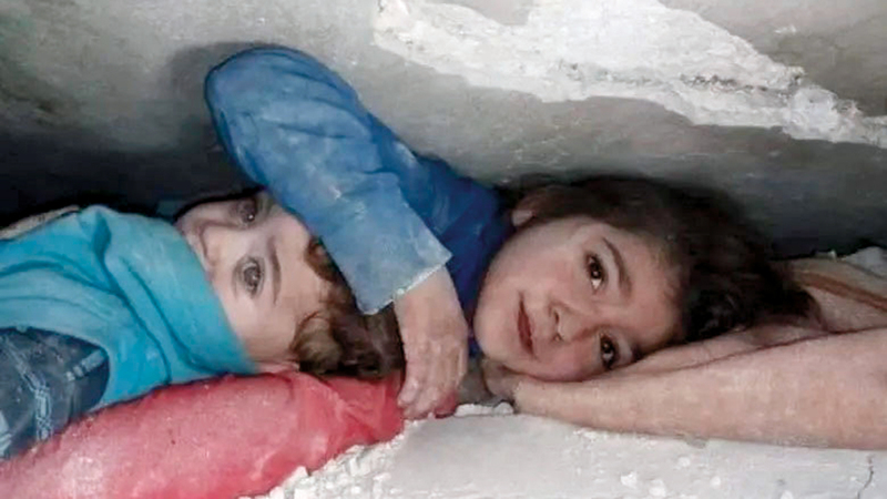 طفلة تحمي شقيقها بيدها وتطلب من المسعف أن يخرجها من تحت الأنقاض.  أرشيفية
