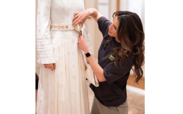الصورة: هكذا تضع ملكة الأردن اللمسات الأخيرة على فستان ابنتها