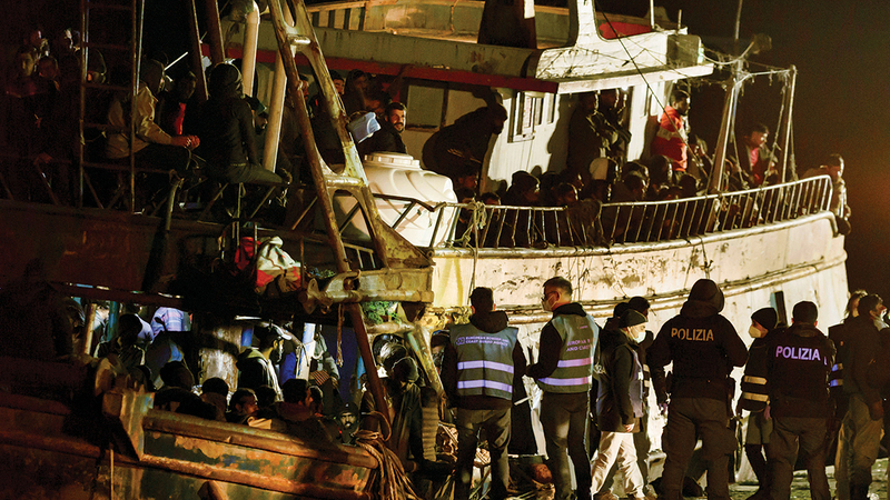 الشرطة تفحص قارباً مع نحو 500 مهاجر في ميناء كروتوني بجنوب إيطاليا. أ.ب