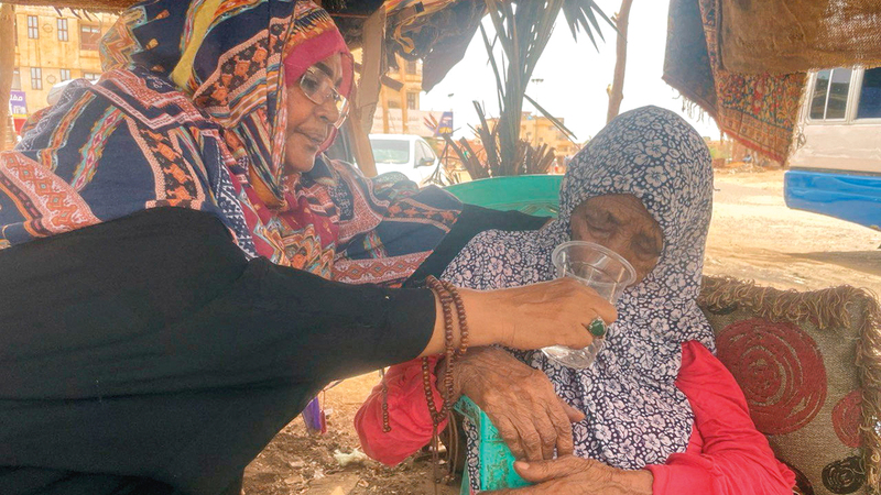 عجوز سودانية تتلقى المساعدة لشرب الماء أثناء فرارها من اشتباكات الخرطوم.رويترز