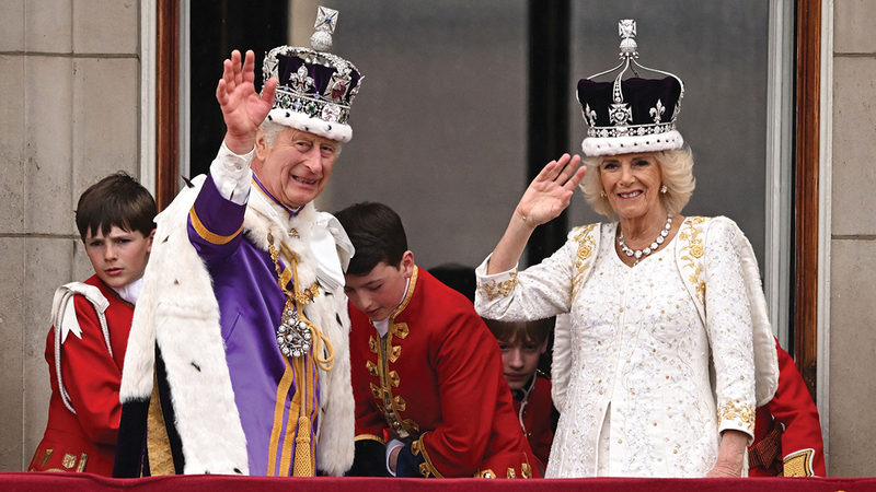 الملك تشارلز الثالث والملكة كاميلا يلوحان من شرفة قصر باكنغهام بعد تتويجهما. أ.ف.ب
